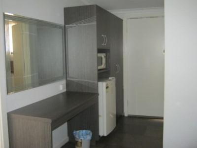 a kitchen with a counter with a microwave and a refrigerator at Parkway Motel in Queanbeyan