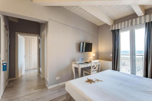 una camera con letto e scrivania con TV di Hotel Nettuno a Cesenatico