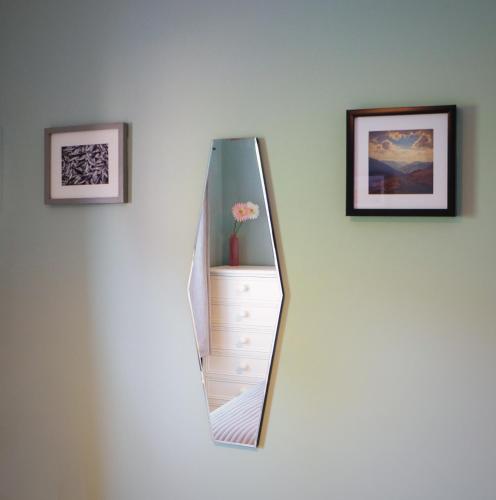 a mirror on a white wall with two pictures at Conwy Cottage in Conwy