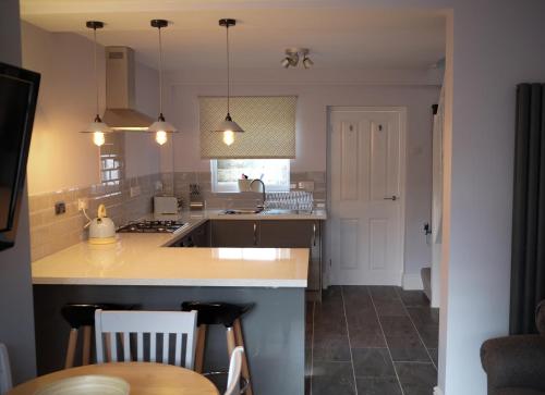 a kitchen with a counter and a sink and a table at Conwy Cottage in Conwy