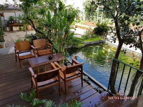 a wooden deck with chairs and a table and a pond at Six Six Garden in Da Lat