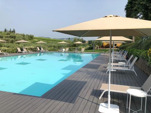 una gran piscina con sillas y sombrilla en Agriturismo Fontanelle, en Cavaion Veronese