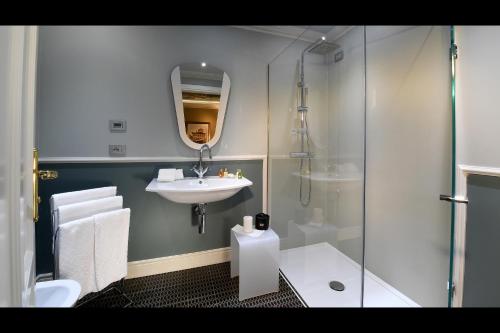 a bathroom with a sink and a glass shower at La Ribezza Boutique Hotel in Monforte dʼAlba