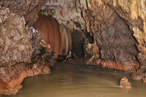a person standing in the water in a cave at Cave Lodge in Pang Mapha