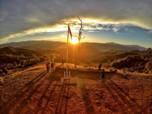 a group of people standing on top of a hill with the sunset at Cave Lodge in Pang Mapha