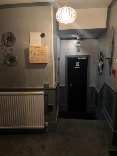 a hallway with a black door and a sign on the wall at Greyfriars Lodge Canterbury in Canterbury