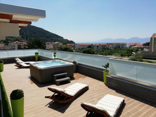 a rooftop deck with a hot tub and lounge chairs at Apartments Villa Katija in Drvenik