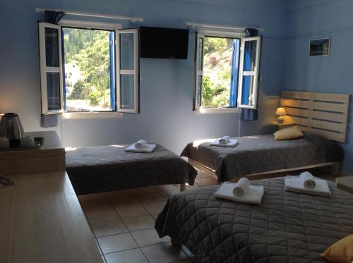 a room with two beds and two windows at Hotel Nostos in Frikes