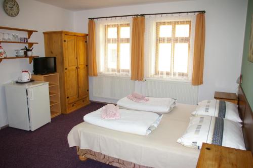 a room with two beds and a television and two windows at Penzion Koudela in Česká Kamenice