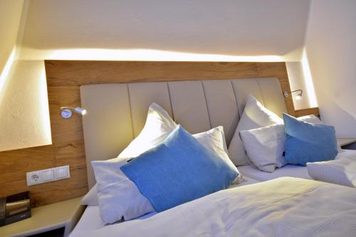 a bedroom with a white bed with blue pillows at Hotel & Restaurant Zum Deutschen Hause in Kirchhatten