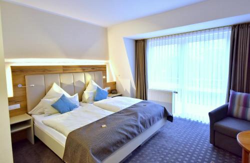 a hotel room with a large bed and a chair at Hotel & Restaurant Zum Deutschen Hause in Kirchhatten