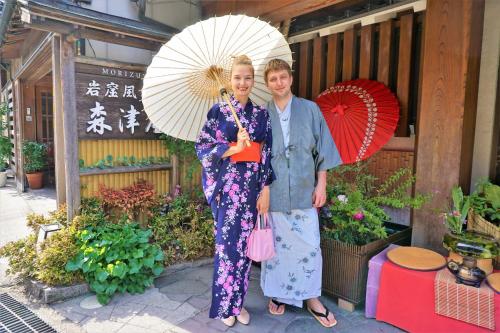 a man and woman standing next to each other holding umbrellas at Morizuya in Toyooka