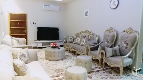 a living room with a couch and chairs and a tv at زائر الشمال للشقق الفندقية in Sakakah