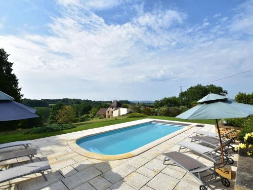 einen Pool mit Stühlen und einem Sonnenschirm in der Unterkunft Cosy holiday home with swimming pool in Mouzens