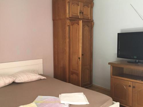 um quarto com uma cama, uma televisão e um armário de madeira em Apartment Aleksandra em Bar