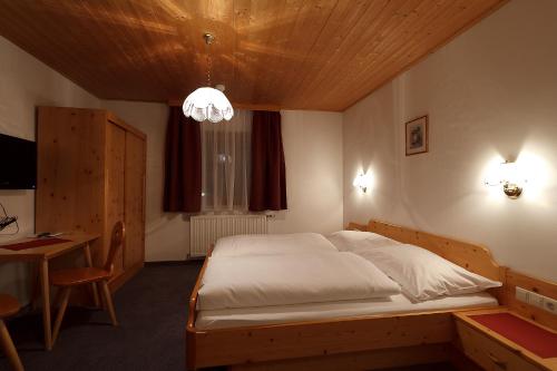 a bedroom with a large bed with a wooden ceiling at Hotel Garni Feichter in Schladming