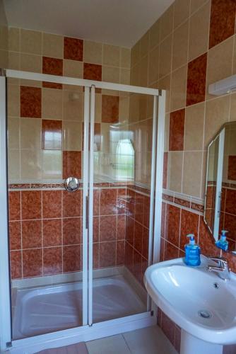 a bathroom with a shower and a tub and a sink at Kilcar Lodge in Kilcar