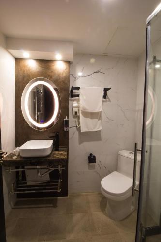 a bathroom with a toilet and a sink and a mirror at Hotel Mellasse in Tissemsilt