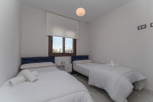 ピラール・デ・ラ・オラダダにあるLa Belle Plage by Mar Holidaysのベッド3台と窓が備わる客室です。