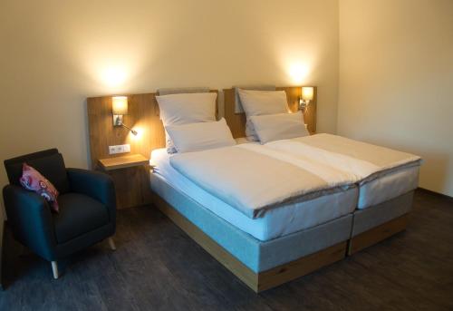 1 dormitorio con 1 cama grande y 1 silla en Hof Hahnenberg, en Wagenfeld