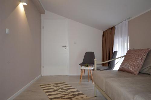 a bedroom with a bed and two chairs and a window at Villa Aba apartments in Sarajevo