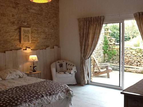 - une chambre avec un lit, une chaise et une porte coulissante en verre dans l'établissement Le Champêtre, à Bazoges-en-Pareds