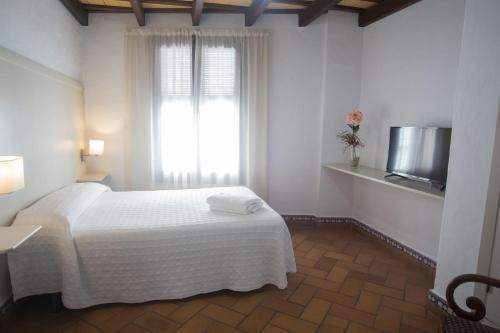 1 dormitorio con cama blanca y ventana en Hostal Santa Catalina, en Conil de la Frontera