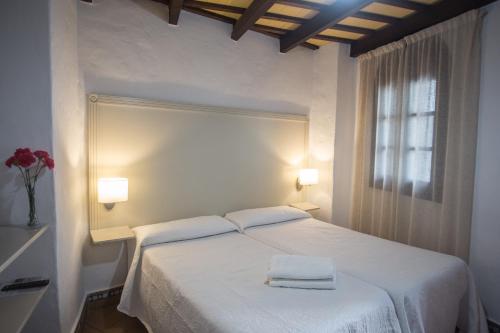 a bedroom with a white bed with two towels on it at Hostal Santa Catalina in Conil de la Frontera