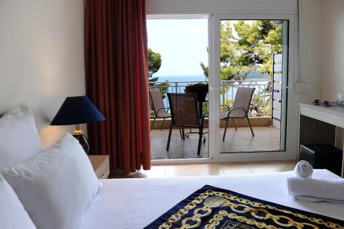 a bedroom with a bed and a balcony with a view at Rodon Loutra in Agia Paraskevi