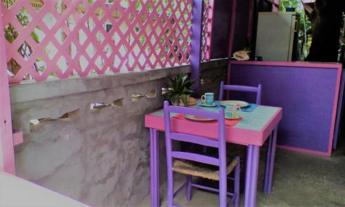 różowy i fioletowy stół oraz dwa fioletowe krzesła w obiekcie Somewhere Special Guesthouse w mieście Gros Islet