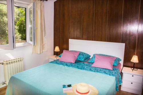 a bedroom with a blue bed with pink and blue pillows at Holiday Home Laurea in Supetar