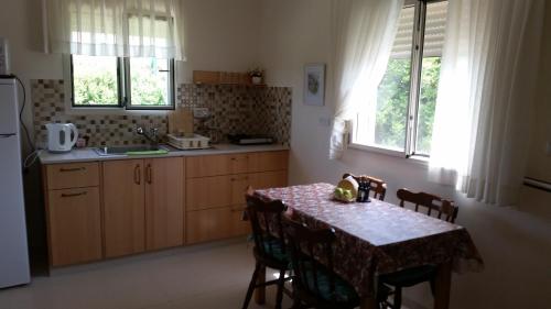 eine Küche mit einem Tisch und Stühlen sowie eine Küche mit einem Kühlschrank in der Unterkunft Beit Haner Moshav Dor in Dor