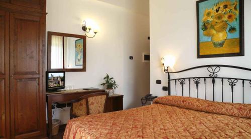 a bedroom with a bed and a desk and a mirror at Colleverde Country House & SPA Urbino in Urbino