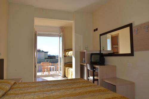 a hotel room with a bed and a mirror and a balcony at Hotel Mirage in Milano Marittima