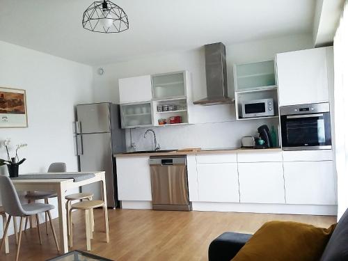 een keuken met witte kasten en een tafel met stoelen bij Nant'Sud Loire in Nantes