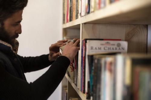 a man picking up a book from a book shelf at Ree Hostel in Leh
