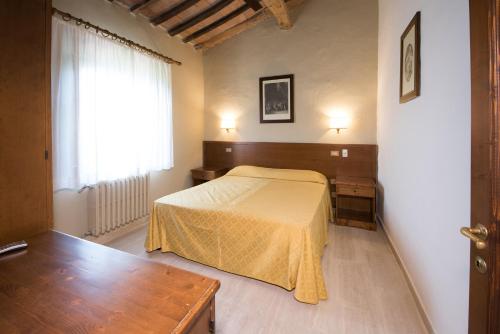 a bedroom with a bed and a table and a window at Tenuta Decimo - Villa Dini in San Gimignano