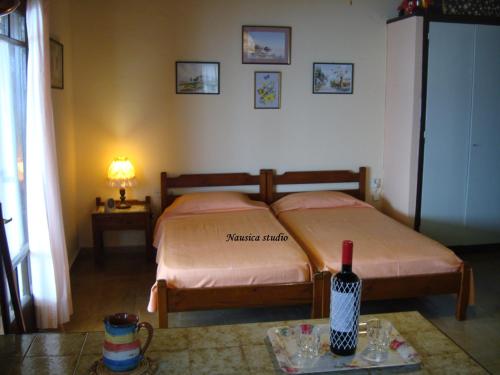 ein Schlafzimmer mit einem Bett und einem Tisch mit einer Flasche Wein in der Unterkunft Studio Nausica... a sense of paradise! in Agia Pelagia Chlomou