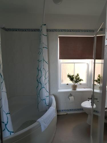 a bathroom with a tub and a toilet and a window at Waterfront Hotel in Deal