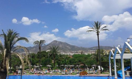 a resort with a pool and palm trees and a mountain at Benal Beach in Málaga
