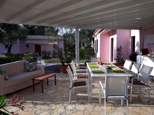 a patio with a table and chairs and a couch at Holiday Home Matthäus am Corfutrail, Ferienoase im Olivenhain 3 km zum Meer in Giannádes