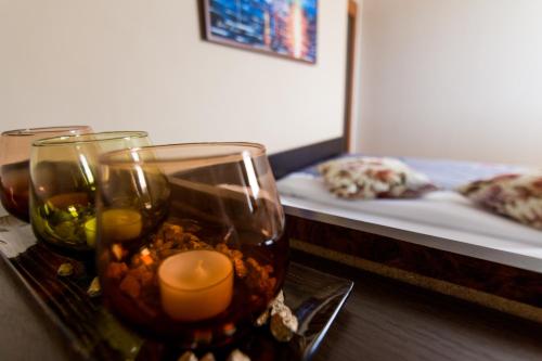 a table with two glasses and candles and a bed at F Apartmani Kragujevac in Kragujevac