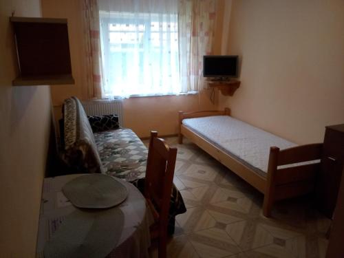 a small room with a bed and a table and a window at OLEŃKA in Darlowko