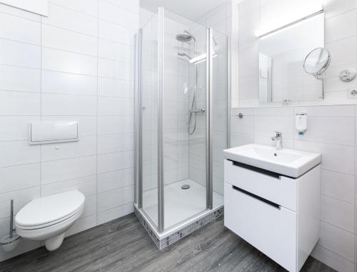 a white bathroom with a shower and a toilet and a sink at Hotel Spree-idyll in Berlin