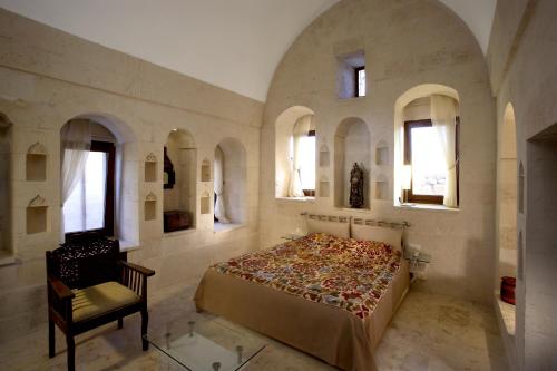 a bedroom with a bed and a chair and windows at Kasr-i Nehroz Hotel in Midyat