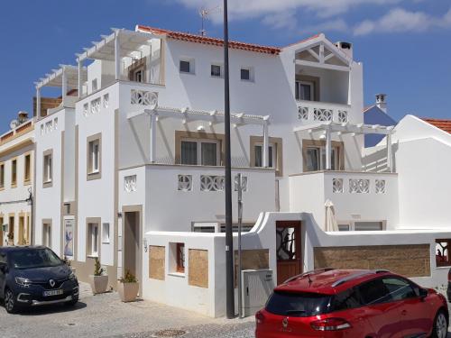 um carro vermelho estacionado em frente a um edifício branco em Guarda Rios em Vila Nova de Milfontes