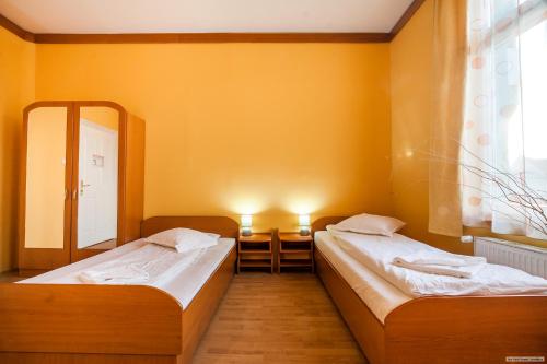 two beds in a room with yellow walls at Szilagyi Hotel&Restaurant in Gheorgheni