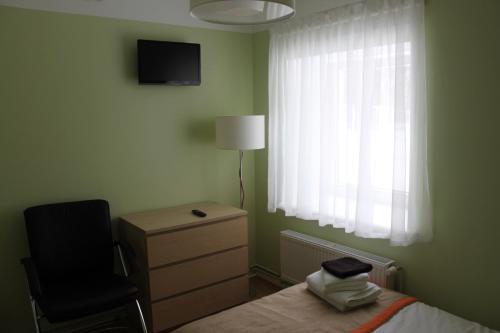 a bedroom with a bed and a chair and a window at Martas Nams in Ventspils
