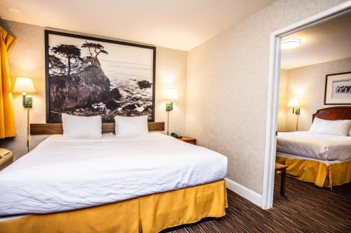 a hotel room with two beds and a painting on the wall at Pelican Inn in Monterey
