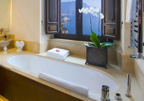 a bathroom with a large tub with a plant in it at Monastero Santa Rosa Hotel & Spa in Conca dei Marini